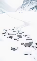 a snowy mountain side road with rocks and trees