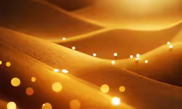 a yellow lit desert area with light reflecting off the sand