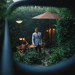 a man standing under an umbrella in a garden