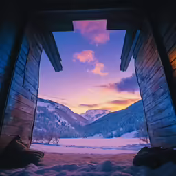 an open cabin in the snow overlooking a mountain range