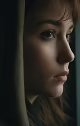 a woman looks out of a window while wearing a scarf