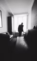 a man standing in a room looking out of a window