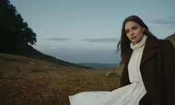 a woman standing alone in a field of tall grass