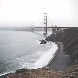 fog obscures the golden gate bridge from the beach below