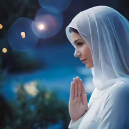 a young woman praying in a white outfit
