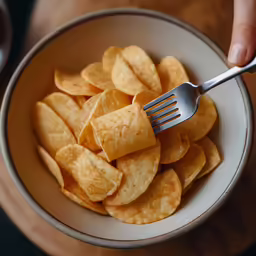 a fork in a bowl of potato chips