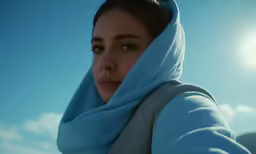 a woman in a blue scarf stands outdoors