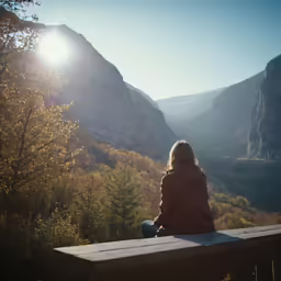 the person is sitting on a bench by the mountains
