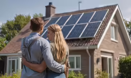 a woman and man standing outside of a small home
