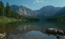 the sun shining on the mountains as water reflects in the surface of a lake