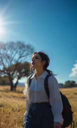 a woman with a backpack is walking through the grass