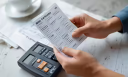 person holding a check in their hand, with papers nearby
