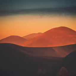 a sun rises over a mountainous terrain with mountains