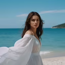 a young woman standing on the beach in a white dress