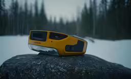 a yellow and black device on top of a large rock