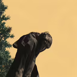 a person in black jacket next to a tree