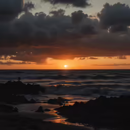 a man is standing on a rock in the ocean as the sun rises