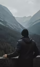 a man stands looking out over a mountain range