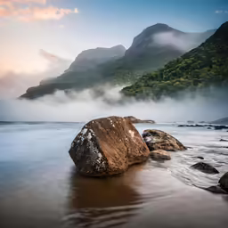 rocks with water in front of them and mountain in background