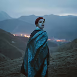 a woman standing on top of a mountain under a blanket