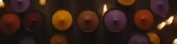 several rows of colored candles on a wall