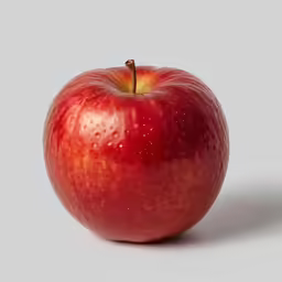 a red apple on a grey background with a few drops