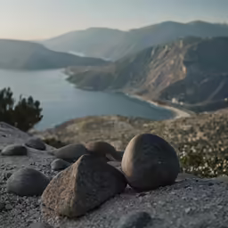 three stones are in the sand near water