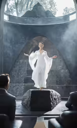 a woman in a dress on top of a rock