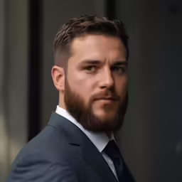 a young man in suit and tie staring at something