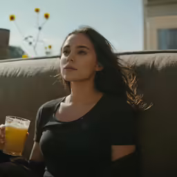a woman sitting on the couch and holding up a glass
