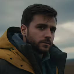 a man with beard wearing a parka in a field