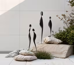 three small sculptures on cement placed near plants