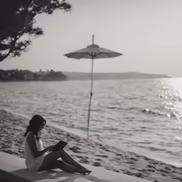 a girl with an umbrella is sitting by the ocean