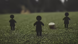 group of black paper men standing in grassy area