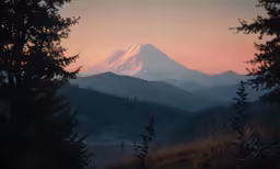 the sun sets behind a mountain as seen through some trees