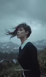 a woman with long hair standing on a hill side
