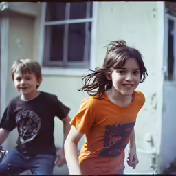 two little kids running down the sidewalk together