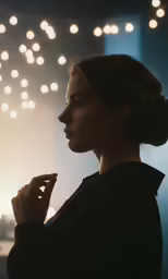 the woman is standing by the window with her hands under her chin