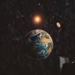 the planet earth sits in space with a bright light above it