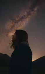 a person standing in a field with the stars in the sky above them