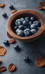 a wooden bowl full of blueberries and leafy leafs