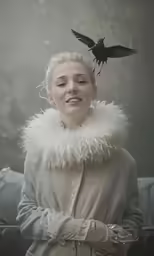a woman is standing in the rain holding a bird on her head