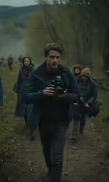 there is a man walking down a trail with his camera