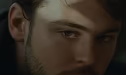 a bearded man looks intently into the camera