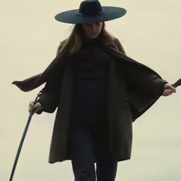 a woman walking down a street with a black hat