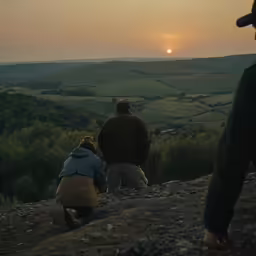 two people overlooking the sunset from a grassy area