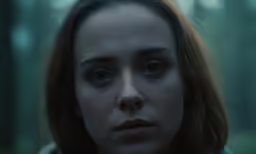 a young lady is in the woods looking into the distance
