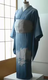 a blue and grey kimono sits on display next to windows