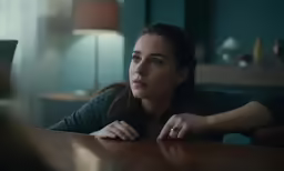 a woman leaning on a table with her hand resting on her knees