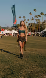 a beautiful young blond woman walking down a grassy field